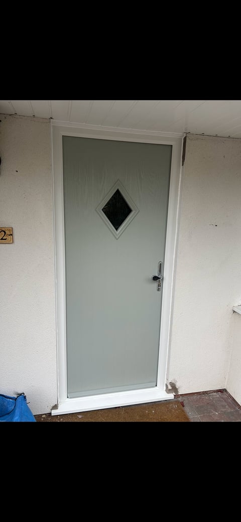 Light green door with white frame and diamond-shaped window mounted in white wall of an interior space